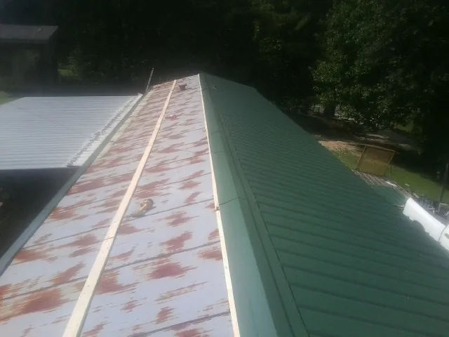 Old rusted panels beside newly installed green metal roofing — Wind Damage Roof Repair by Roofing Brothers in Winter Springs