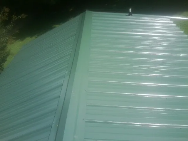 New green metal panels meeting at the ridge of a roof — Flat Roof Repair work by our crew in Winter Springs