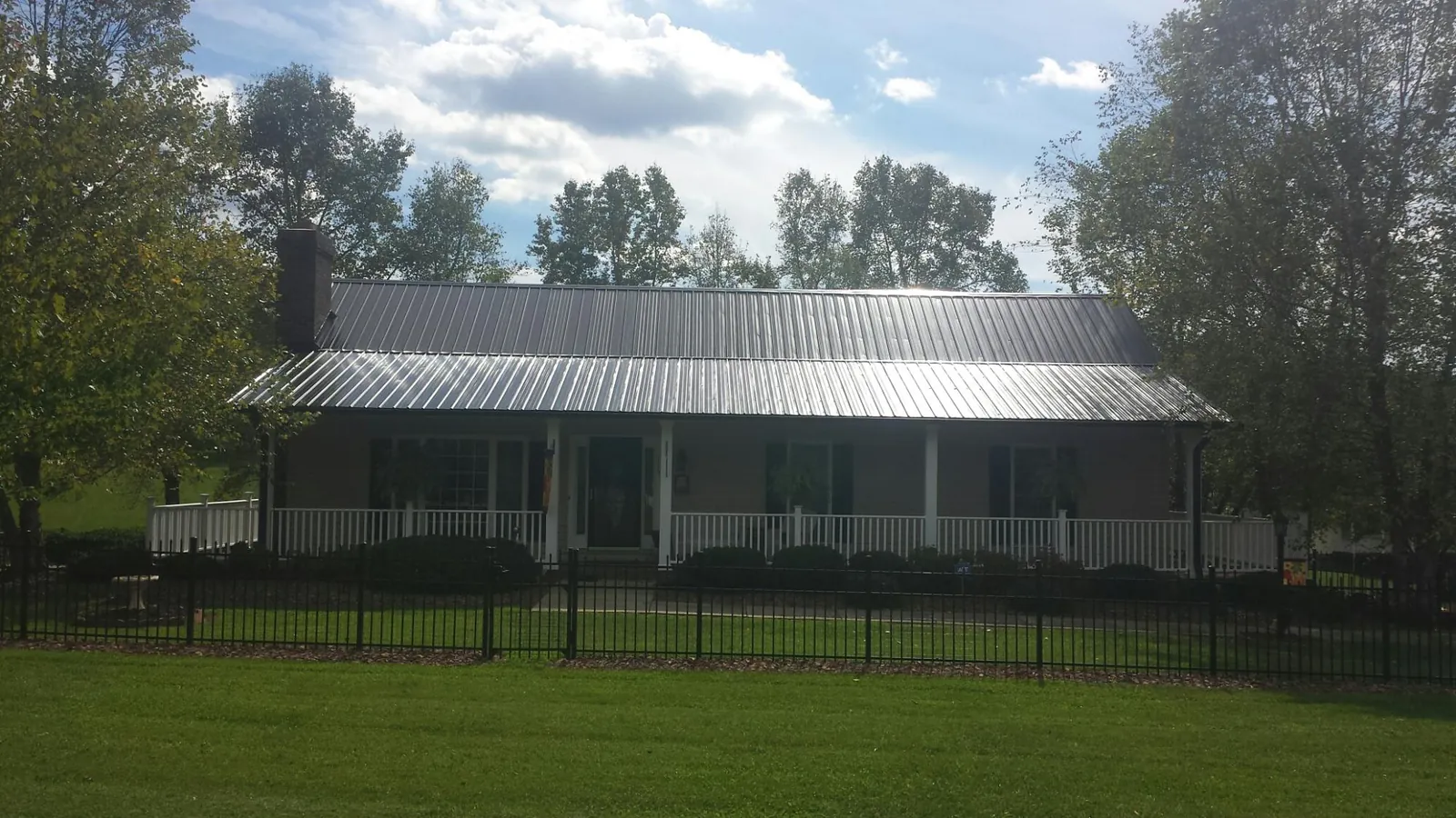 Gray metal roof on a brick ranch with a full width front porch — Gutter Guard Installation work by our crew in Winter Springs