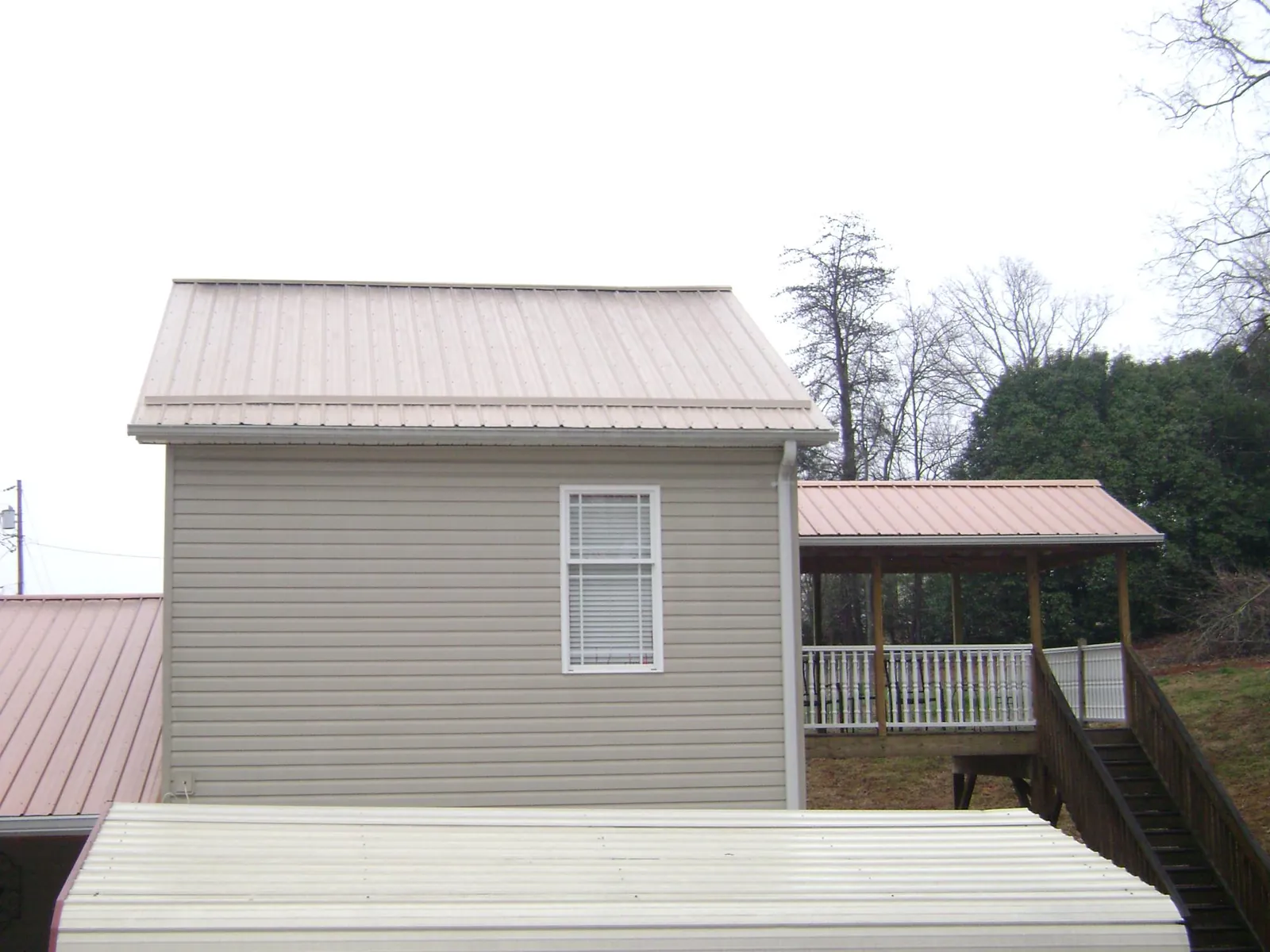 Tan metal roofs on a two story addition and attached porch, from a Roof Replacement job in Winter Springs