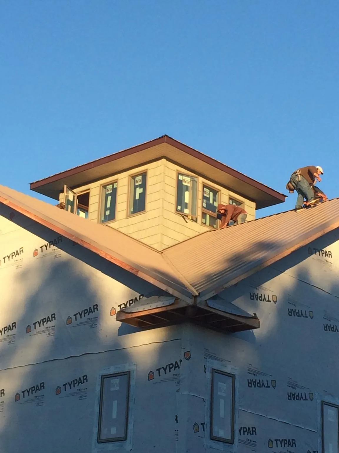 Roofers working around a rooftop cupola on a new metal roof at sunset — Roof Waterproofing in Winter Springs by Roofing Brothers